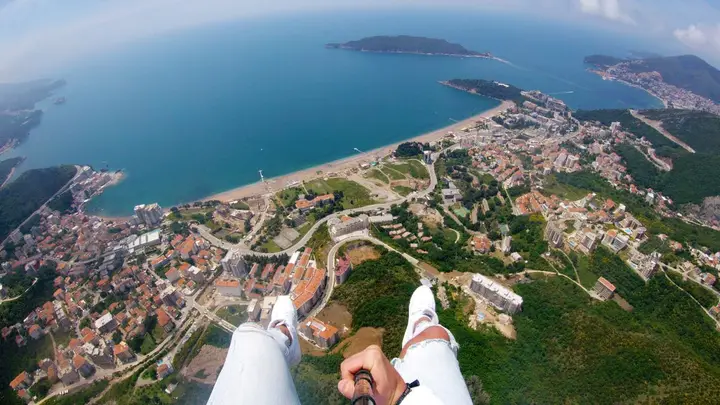 Tandem paraglider gliding along the Budva coastline with the Adriatic below